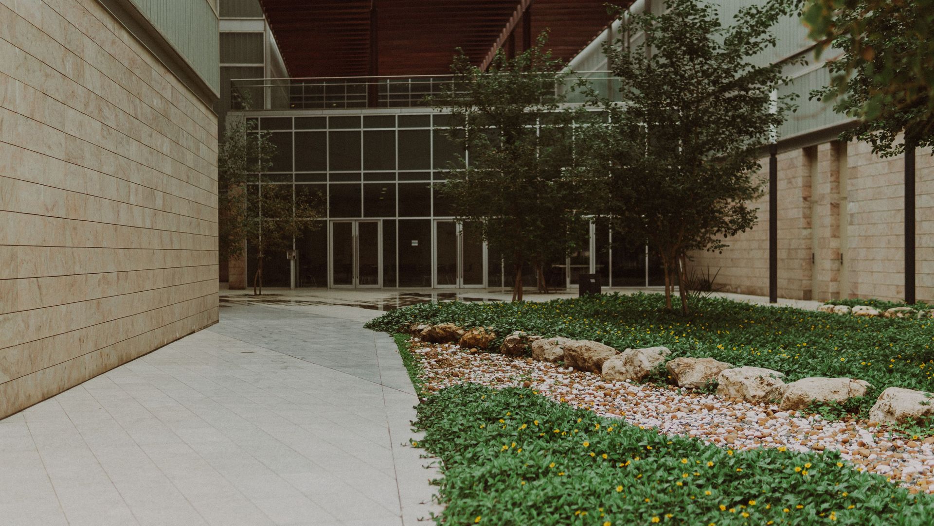 Entrance of a modern building with lush greenery in Kuwait City.